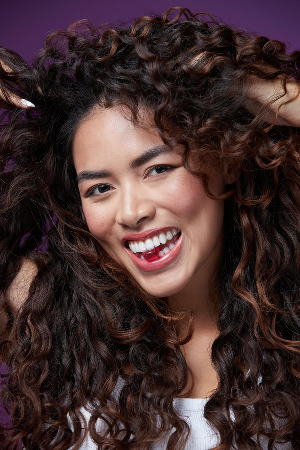 a woman with long curly hair smiling